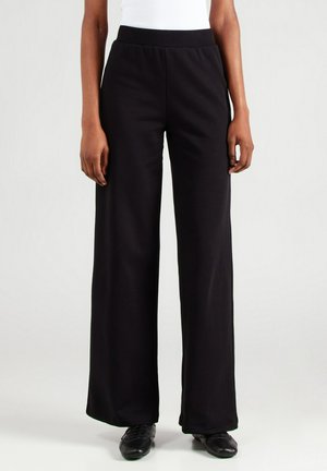Schwarze weit geschnittene Hose aus weichem Stoff, mit einem elastischen Bund und einer glatten Textur, die eine lockere Passform bietet, geeignet für verschiedene Outfits.
