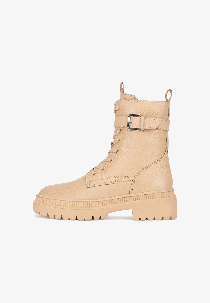 Béžové kožené kotníkové boty s šněrováním vpředu, postranním detailním přezkovým uzávěrem a robustní gumovou podrážkou s horizontálními drážkami.