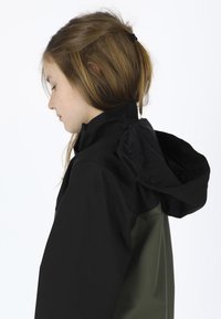 Black and olive green waterproof jacket with a fitted collar and hood, featuring smooth, matte fabric and a structured design.