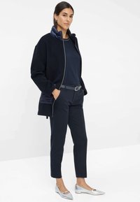 Giacca in fleece blu navy con colletto trapuntato, abbinata a pantaloni blu navy e ballerine argentate. Design semplice, texture morbida e tasche funzionali.