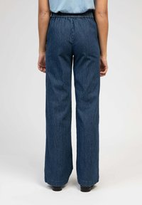 Pantalons à jambes larges en tissu texturé bleu foncé avec des rayures verticales. Dotés d'une taille élastique et de revers retroussés.