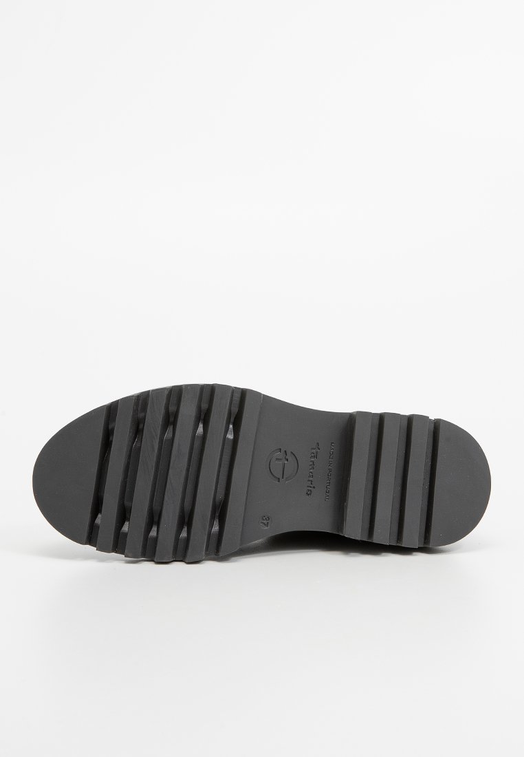 Suola di scarpa in gomma, nera, con texture e scanalature orizzontali per una migliore aderenza, caratterizzata da una punta arrotondata e un'impronta del logo. Design piatto e liscio.