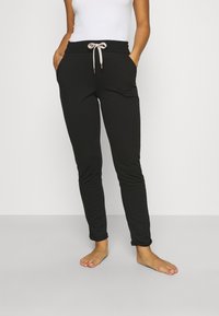 Zwarte joggerbroeken met een elastische tailleband, een trekkoordsluiting, zijzakken en een slanke pasvorm. De stof is zacht en rekbaar.