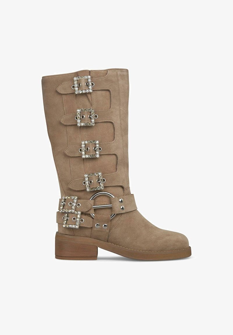 Bota de ante hasta la rodilla en color marrón claro con hebillas y acentos de rhinestones. Presenta una puntera cuadrada y un tacón de madera apilada.