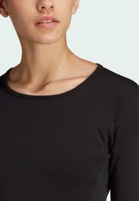 Maglietta nera a maniche lunghe con scollo rotondo, realizzata in materiale di cotone elastico, caratterizzata da una texture liscia e dettagli di cucitura semplici.