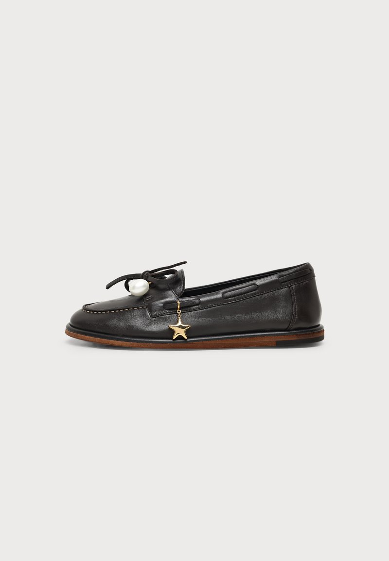 Mocassin en cuir noir avec un nœud, une grosse perle blanche et un petit charme étoile doré sur le côté, avec des détails de semelle marron.