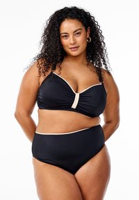 Juodas maudymosi kostiumėlis, turintis raukšlėtą viršutinę dalį su centriniu akcentu ir reguliuojamomis petnešėlėmis, derinamas su aukšto juosmens apačia su kontrastinga apdaila.