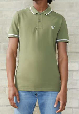 Olivgrünes Poloshirt mit kurzen Ärmeln, weißem Kragenbesatz, dreiknöpfiger Knopfleiste und aufgesticktem CK-Logo auf der Brust.