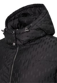 Svart vadderad jacka med hög krage, quiltad struktur, dragkedja och metalliska accenter. Mönstrat tyg ger djup.