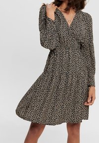 Blumenkleid in Schwarz mit kleinen rosa und cremefarbenen Blumen. Lange Ärmel, taillierte Passform und ausgestellter Rock. Weiche Stofftextur.