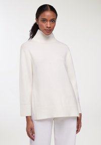 Maglione bianco a collo alto realizzato in materiale morbido, con polsini e orlo a coste, dal taglio casual e con spacchi laterali per un maggiore comfort.