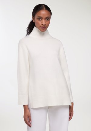 Maglione bianco a collo alto realizzato in materiale morbido, con polsini e orlo a coste, dal taglio casual e con spacchi laterali per un maggiore comfort.