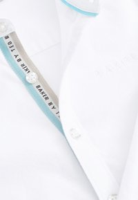 Valge kraega särk sinise äärisega, bränditud nööpidega ja "Baker by Ted" tekstiga krae siseküljel.