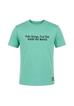 T-shirt vert à manches courtes avec texte noir "Palm Springs, Surf Club, RIDIN'THE WAVES" centré sur la poitrine et un petit patch logo noir près de l'ourlet inférieur.
