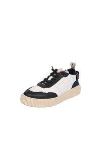 Baskets avec une tige blanche et des accents en cuir noir, une semelle en caoutchouc crème et des lacets noirs. Logo affiché sur le côté.