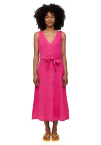 Rosa Leinen-Midikleid mit V-Ausschnitt, Knopfverschluss vorne und abnehmbarem Gürtel. Das Model trägt gelbe Sandalen.