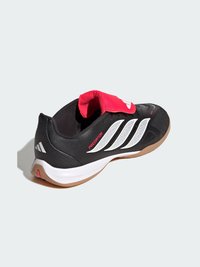 Chaussure de football en salle noire et blanche avec languette rouge, bandes Adidas blanches, semelle gomme et inscription "Predator" sur le côté.