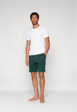 Weißes Kurzarm-T-Shirt und dunkelgrüne Shorts, beide aus weichem Stoff gefertigt. Die Shorts haben Seitentaschen und eine lockere Passform.