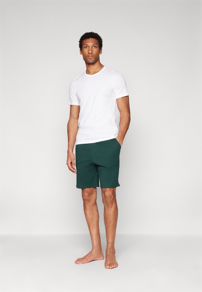 Witte t-shirt met korte mouwen en donkergrijze shorts, beide gemaakt van zachte stof. De shorts hebben zijzakken en een relaxte pasvorm.