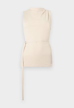 Αμάνικο μπεζ τοπ με υψηλό λαιμό, πλαϊνή υφασμάτινη ζώνη με μεταλλικό κρίκο, ίσια τελείωμα και μινιμαλιστικό σχεδιασμό.