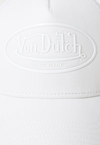 White cap made of textured fabric, featuring an embossed "Von Dutch Originals" logo in the front within an oval frame.
