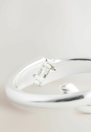 Silver bracelet with a smooth, round shape and a clasp mechanism. Features polished metal texture and subtle reflections.