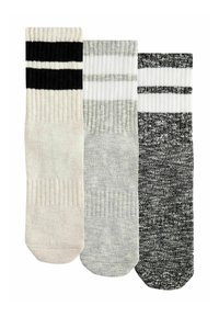 Tre par av ankelsockor: en krämfärgad med svarta ränder, en grå med vita ränder och en svart med gråa fläckar. Ribbad struktur.