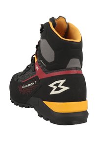 Stivale da trekking nero e rosso con una membrana Gore-Tex, parte superiore testurizzata, suola robusta e dettagli gialli sul tallone e nel marchio.