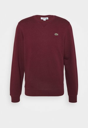 Sweat-shirt bordeaux à manches longues avec col rond, poignets et ourlet côtelés, arborant un petit logo crocodile vert sur le côté gauche de la poitrine.