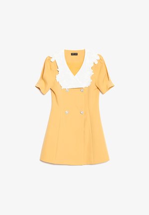 Kort gul kjole med puffermærmer, stor hvit blonderkrage med blomsterdesign og fire dekorative firkantede knapper foran.