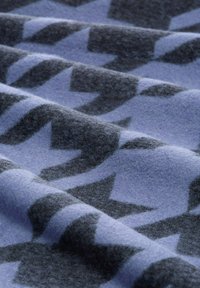 Wollstoff in Blau mit dunkelgrauen Zickzackmustern. Weiche Textur mit einem leicht fähigen Finish, das in Falten fällt.