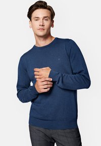 Granatowy, dzianinowy sweter z okrągłym dekoltem, ściągaczami na rękawach i dolnym wykończeniu, z małym logo na piersi. Gładka faktura i dopasowany krój.