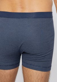 Laivastonsiniset raidalliset bokserishortsit joustavasta kankaasta, joissa on joustava vyötärönauha, vaakasuorat linjat ja tiukka istuvuus.