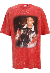 Red oversized t-shirt with a textured finish and a central graphic print of a man in a black jacket featuring various patches.
