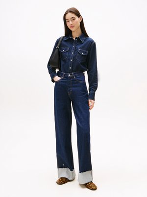 Cămașă din denim de culoare albastră închisă, cu mâneci lungi și două buzunare frontale. Asortată cu blugi largi de culoare albastră închisă, cu tivuri decent franjurate de culoare gri.