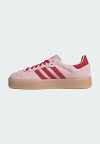 Roze suède sneaker met rode accenten, met een ontwerp van drie strepen, ronde neus en een doorschijnende rubberen zool. Inclusief rode veters.