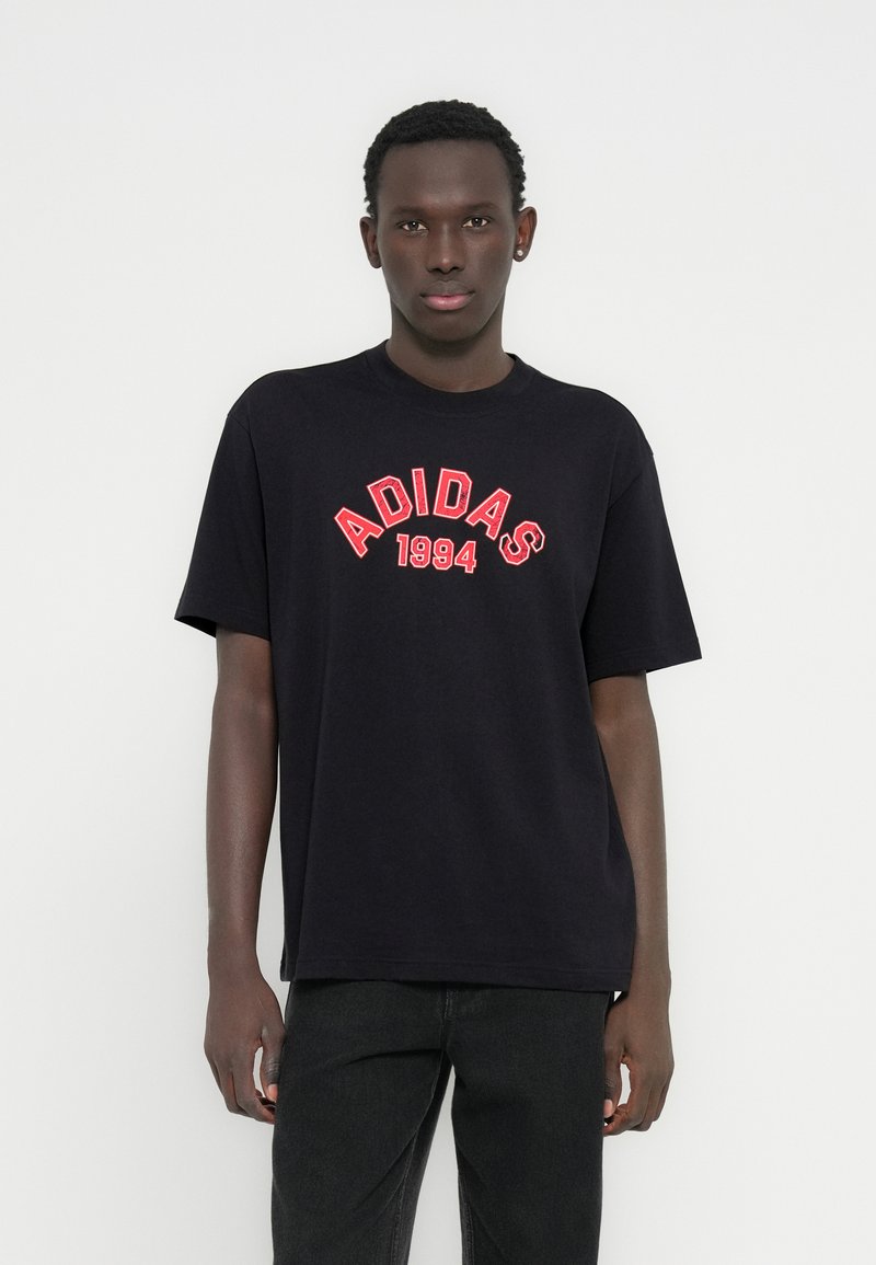 Μαύρο βαμβακερό μπλουζάκι με κόκκινο κείμενο "ADIDAS 1994" σε κυρτό σχέδιο. Κανονική εφαρμογή με κοντά μανίκια και κλασικό λαιμόκοψη.
