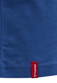 Blå bomullströja med en mjuk textur, med en röd tagg med varumärket "hummel" vid nederkanten.