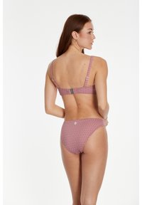 Crveni bikini s uzorkom, prilagodljivim trakama, geometrijskim dizajnom i zaklopkom na leđima, izrađen od rastezljivog kupaćeg materijala.