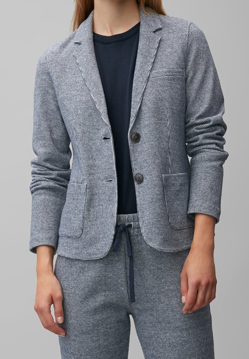 Navy- und weiß karierter Blazer mit zwei Knöpfen, Reverskragen und Fronttaschen, kombiniert mit einer passenden karierter Hose.