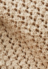 Tissu en crochet beige avec un motif ouvert et aéré de boucles interconnectées et de points texturés.