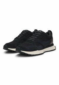 Sneaker neri in suede e mesh con una parte superiore testurizzata, lacci piatti e una suola di colore crema. Presentano un sottile marchio sul lato.
