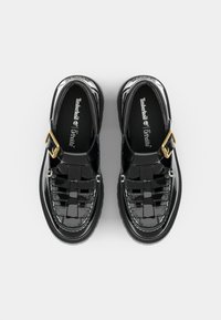 Sapatos de verniz preto com design tecido, detalhe de fivela dourada e palmilhas acolchoadas. Bico arredondado e sola robusta.