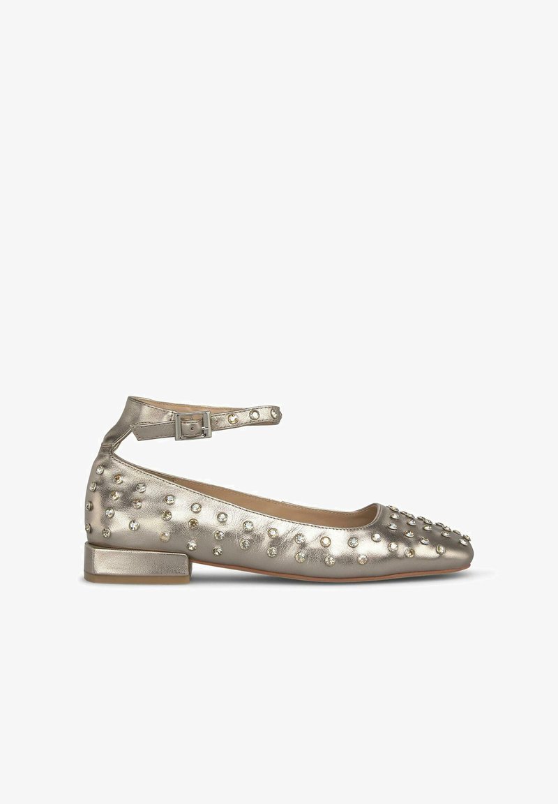 Bailarinas metálicas doradas con puntera redondeada, correa en el tobillo y tachuelas decorativas. Tacón plano con parte superior de cuero suave y detalles texturizados.