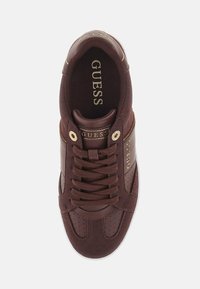 Brune sneakers med en glat læder- og ruskindsoverdel, gyldne akcenter, afrundet tå, perforeret detaljering på siderne og logo på tungen.