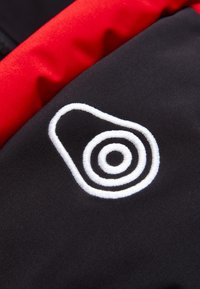 Svart tyg med en slät textur, med en vit broderad spiral-logotyp och en kontrasterande röd kant längs den övre sektionen.