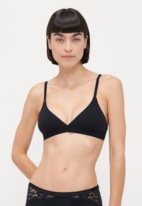 Black triangular bra with thin straps, made of smooth fabric. Features a deep V-neck design and a fitted silhouette. Textured waistband below.