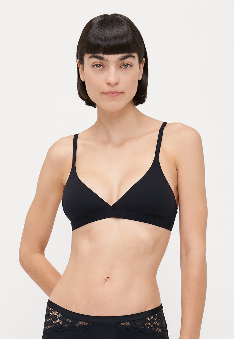 Black triangular bra with thin straps, made of smooth fabric. Features a deep V-neck design and a fitted silhouette. Textured waistband below.