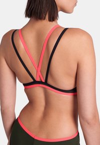 Schwarzer und pinker Sport-BH mit dünnen, verstellbaren, überkreuzten Trägern auf der Rückseite. Glattes Material, minimalistisches Design und kontrastierende Farbakzente.