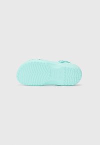 Light blue rubber shoe sole with textured grip pattern, featuring drainage holes and a round button for adjustable fit.